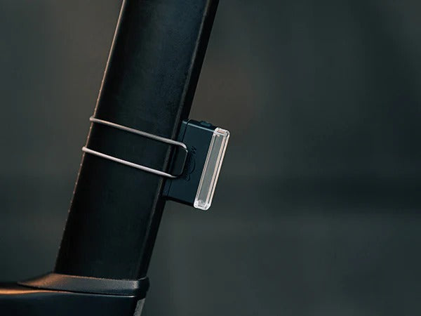 Close up of a rear tail light attached to a bicycle seatpost on a blurred background