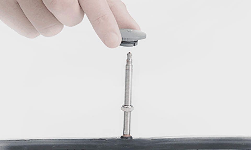 A hand removing a bicycle presta valve core with a tool