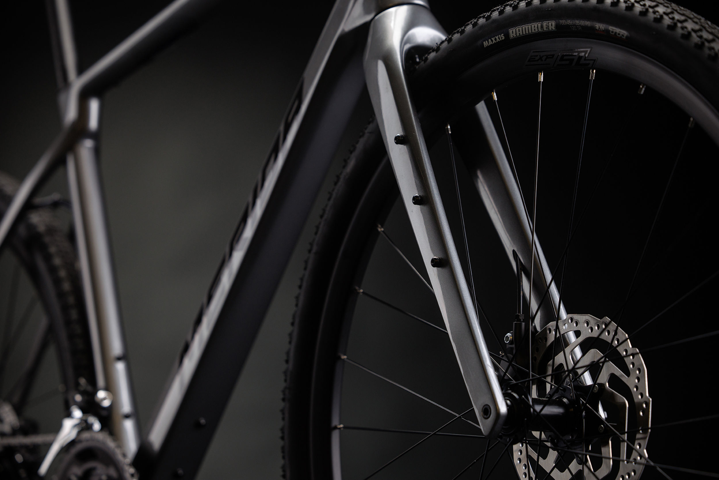 Close-up of a grey Merida gravel bike front wheel and front fork on a dark background