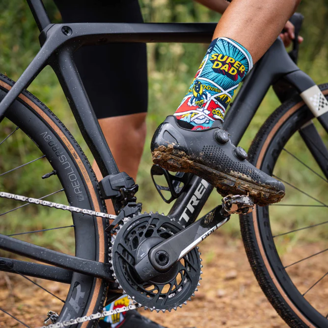 Person riding a bicycle with 'Super Dad' socks on, on a natural background