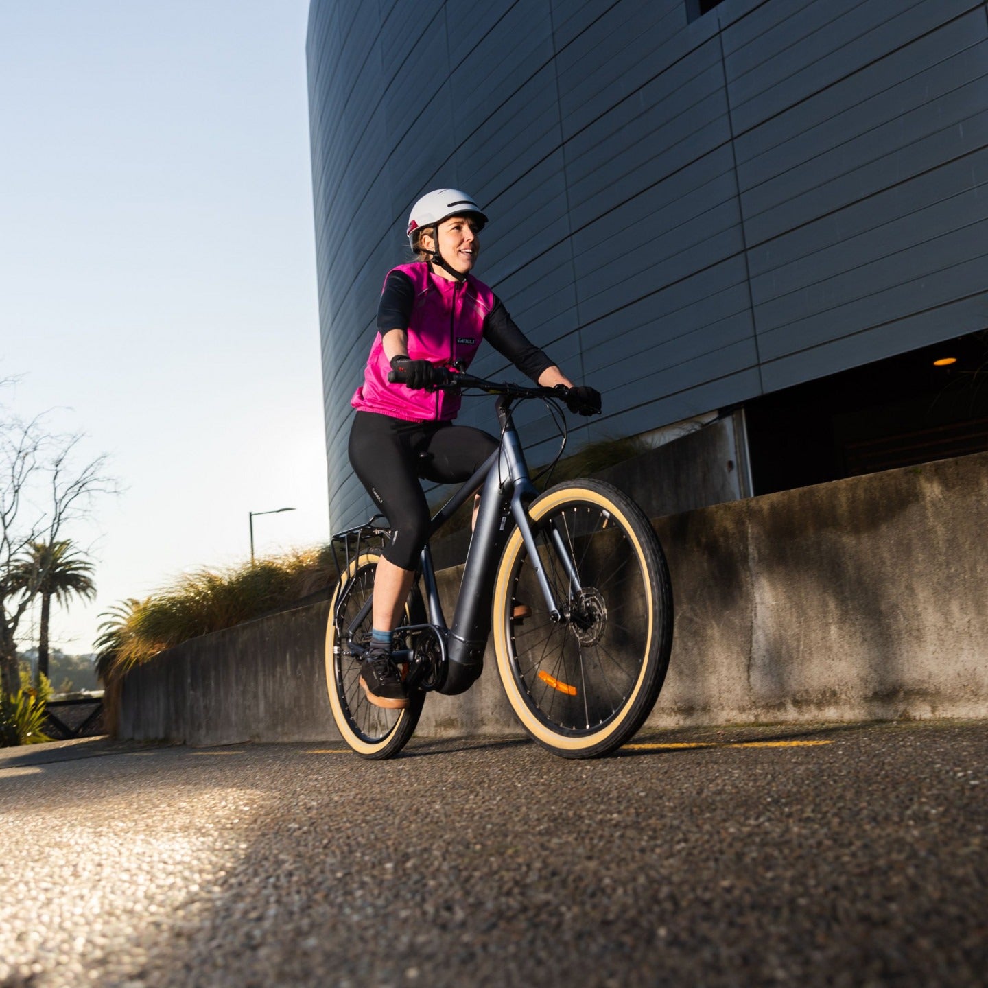 Person riding an electric bike in an urban setting with a modern building in the background