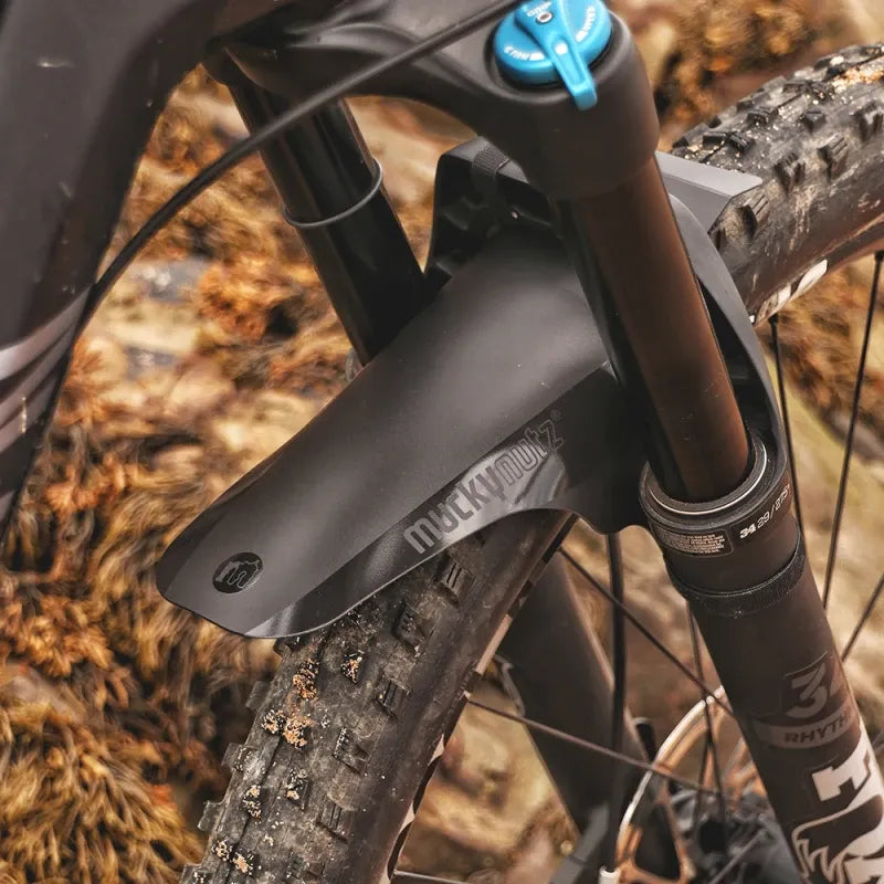 A close up of a Mucky Nuts black face fender mudguard installed on a mountain bike against an outdoor background
