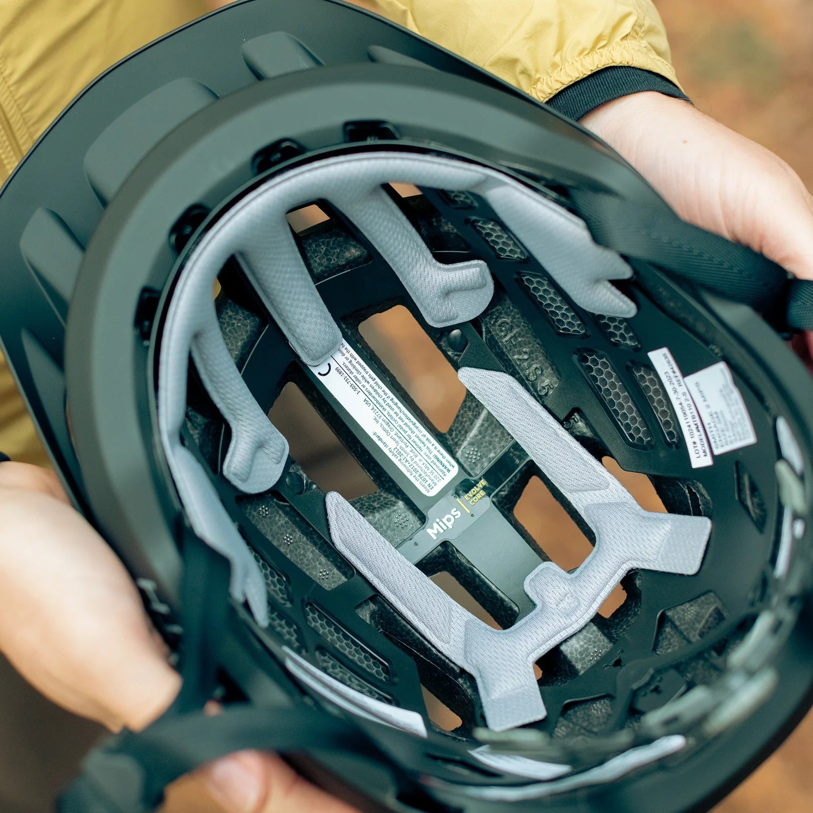 Close-up of a person holding a black mountain bike helmet showing the inside with gray padding.
