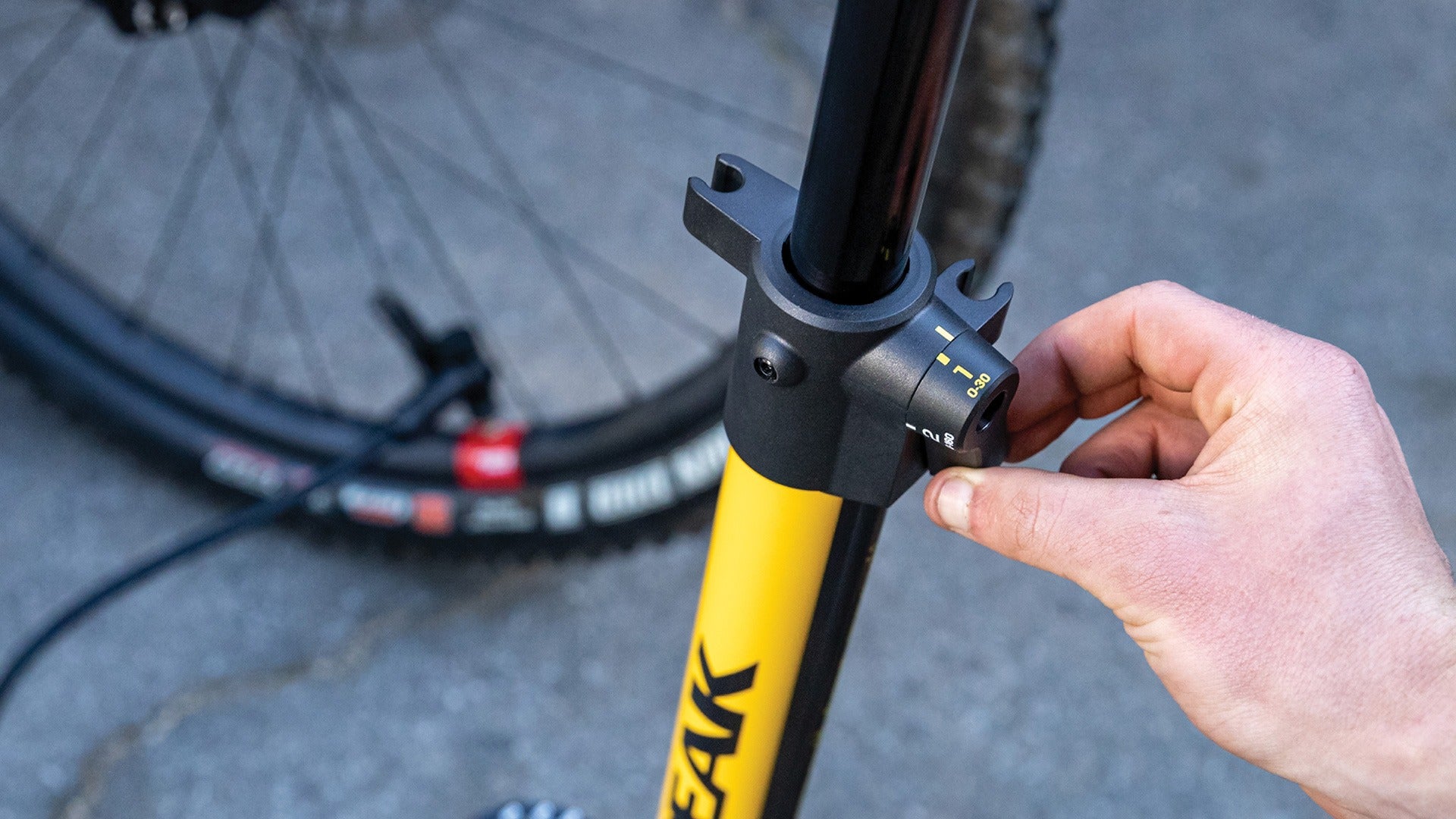 Person adjusting the dial on the Topeak JoeBlow 2Stage Floor Pump against a blurred background