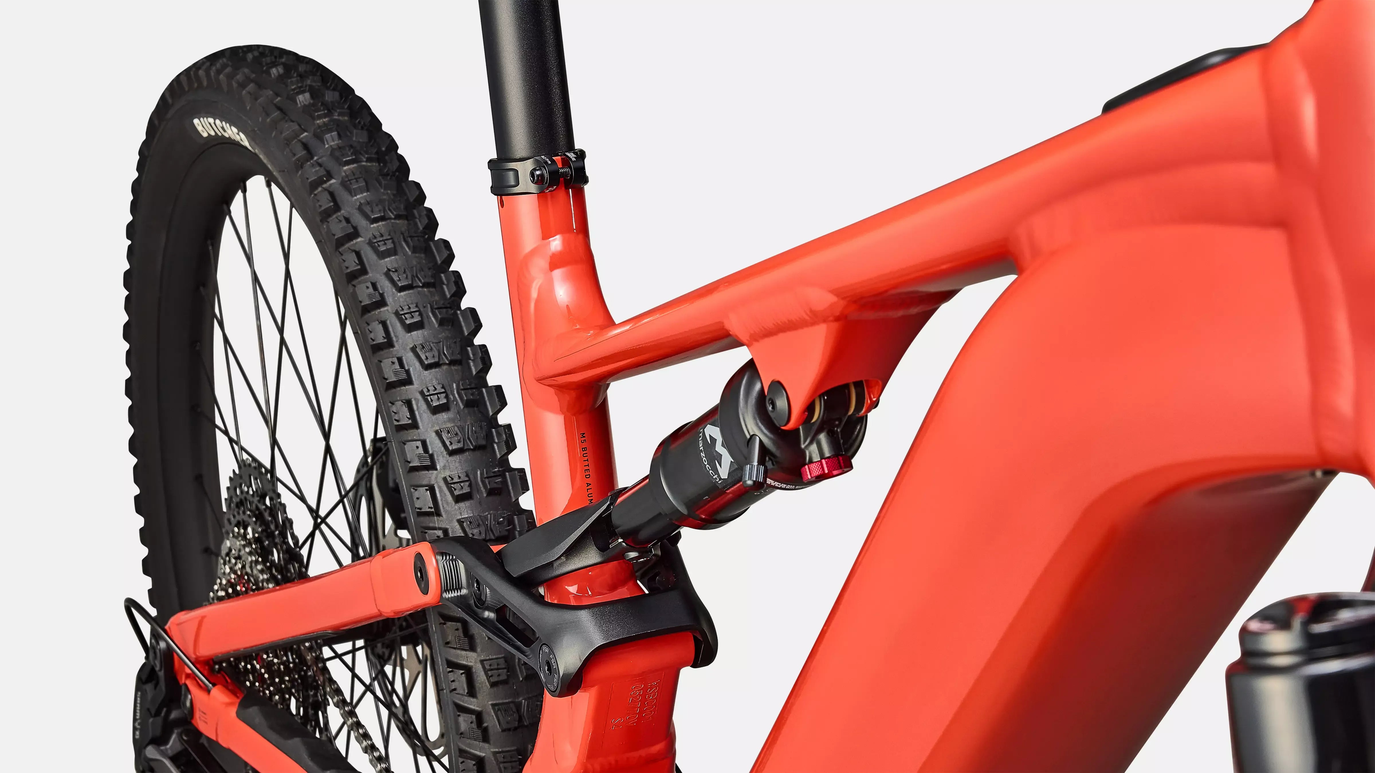 Close-up of a red bicycle dual suspension frame with black components on a light gray background