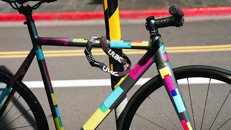 Colorful bicycle with a bicycle lock wrapped around the frame and a pole on a road