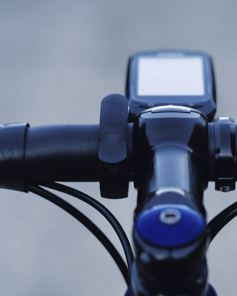 Close-up of road bike handlebar with Knog Bell attached against a blurred background