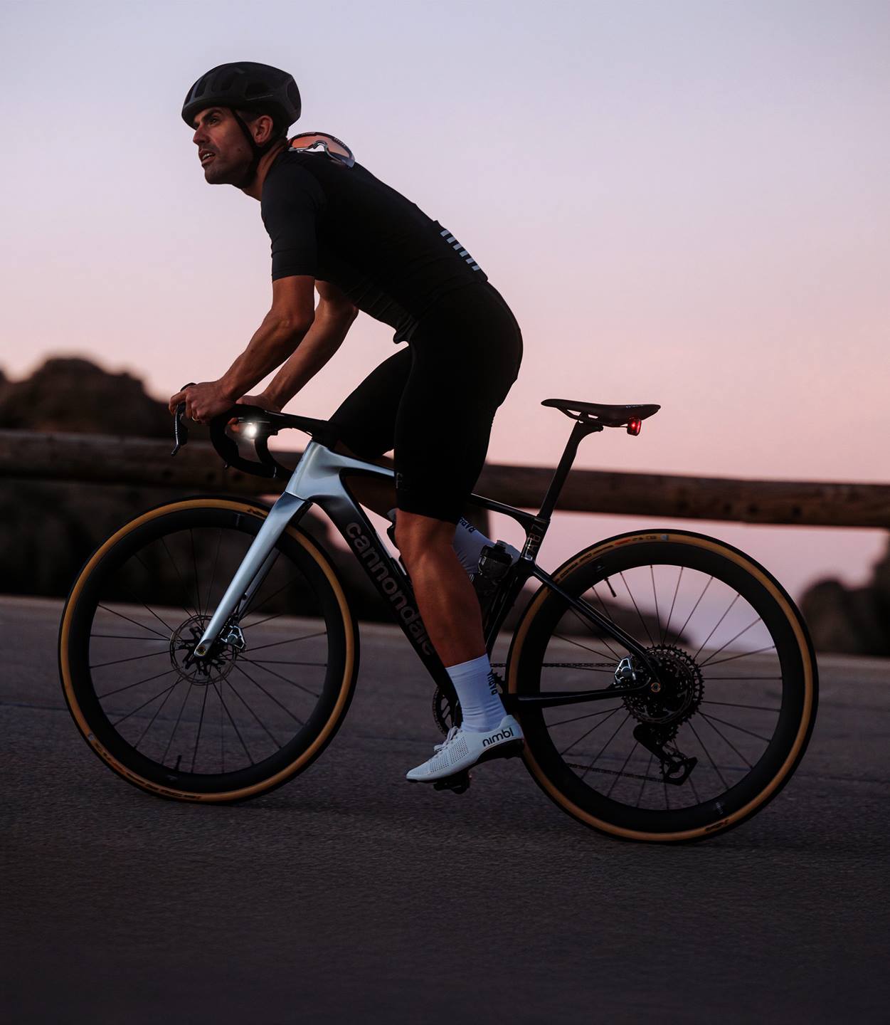 Person riding a Cannondale road bike on a road during sunset