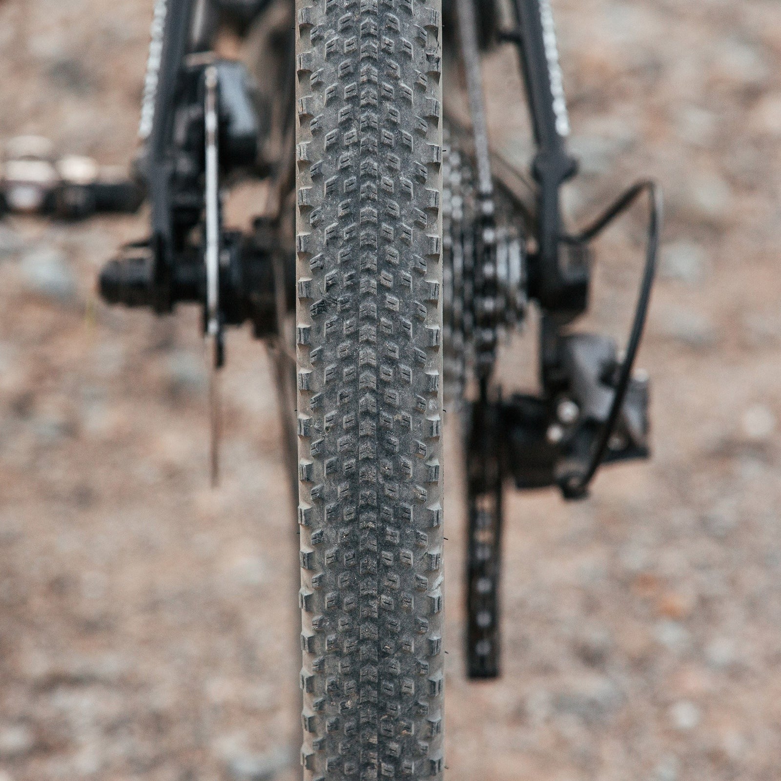 Close up of a dirty Gravel Tyre on a bike with a blurred gravel road in the background