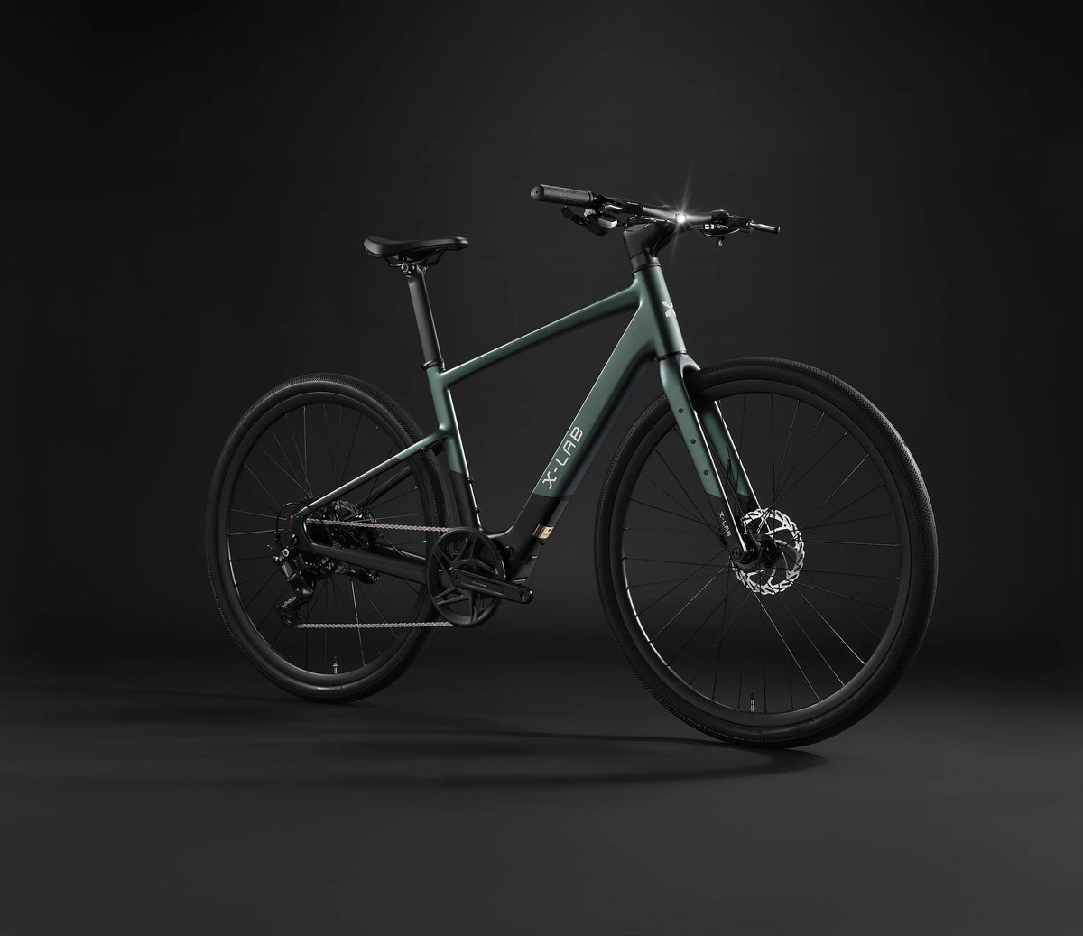 A sleek electric bicycle in matte dark green and black, photographed from a three-quarters angle against a dark studio background. The brand name 'X-LAB' is clearly visible on the down tube.