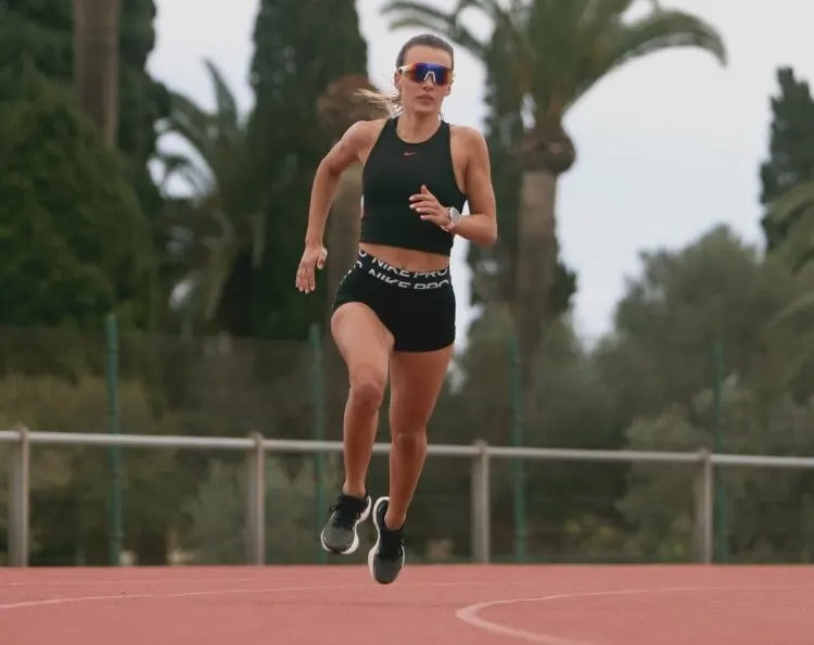 Woman running on a track with trees in the background