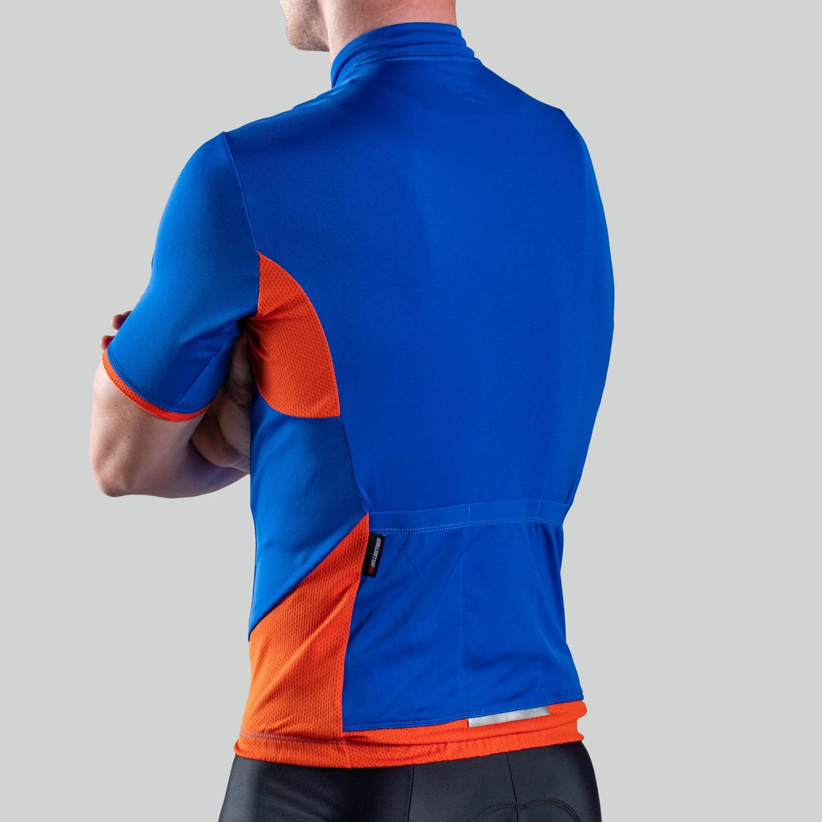 A rear view of a person wearing a blue and orange cycling jersey on a light grey background