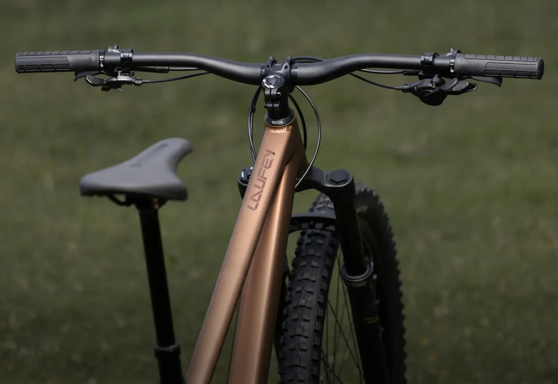 Close-up of a Laufey mountain bike handlebar with a blurred green background