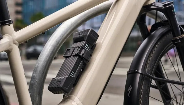 Close-up of a bike with a folding lock attached on bike with an urban street in background.