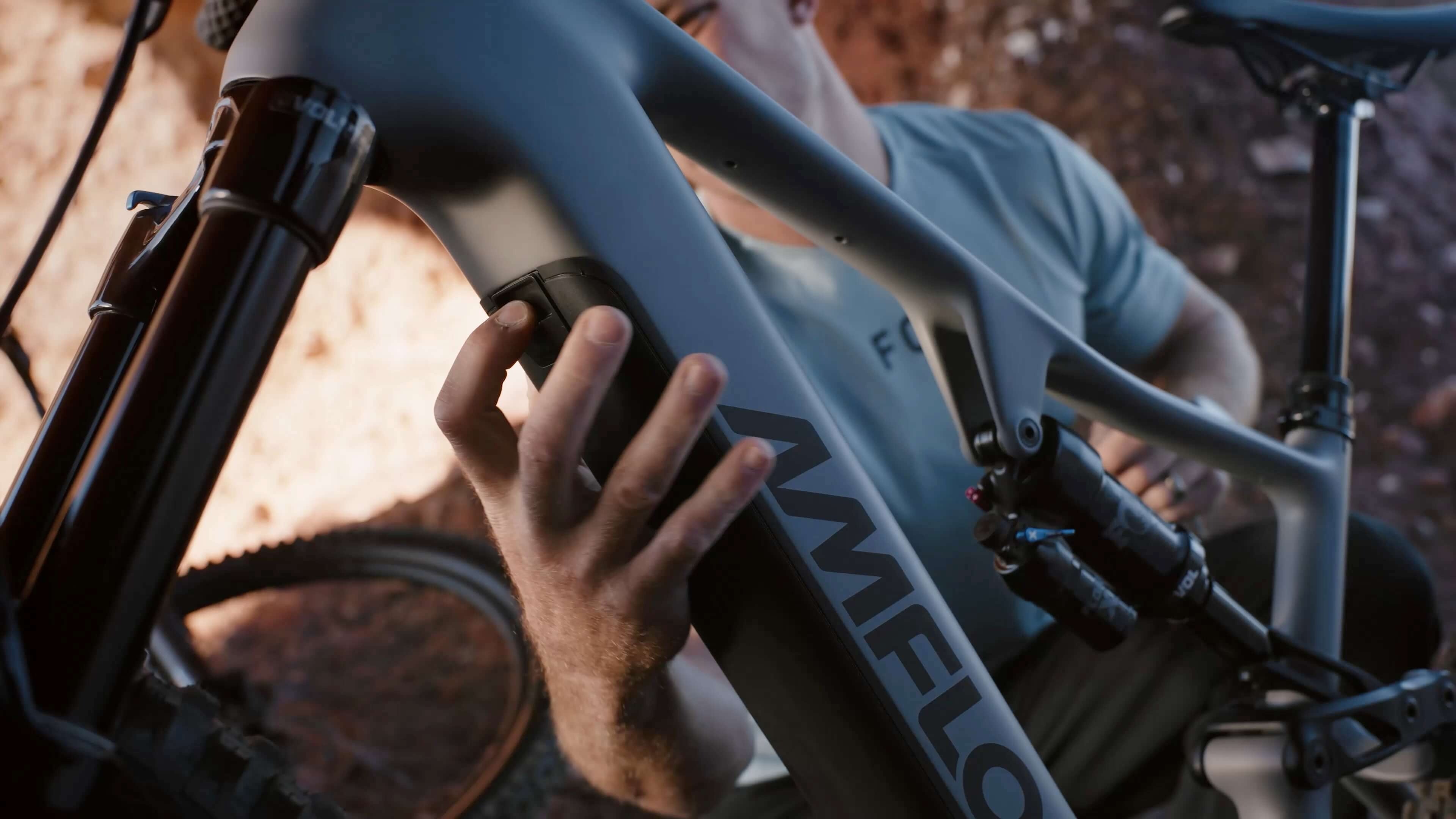 Close-up of a person installing a battery  on an electric mountain bike with 'Amflow' branding.