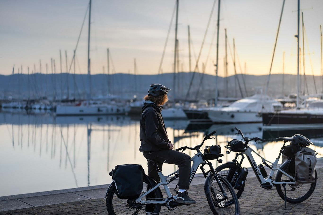 Person sitting on an Amflow Mountain bike by a marina at sunset