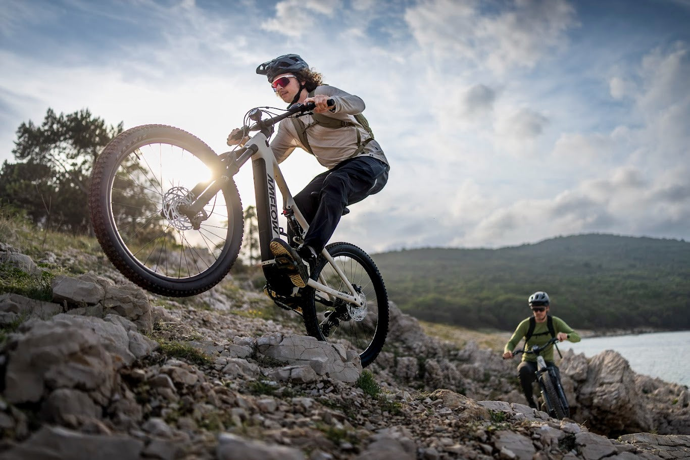 Two mountain bikers riding Amflow E-Bikes on a rocky trail with a scenic background