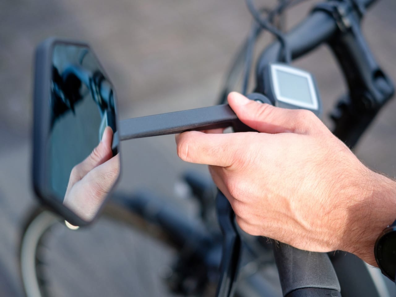 Person adjusting a bicycle mirror with a blurred background