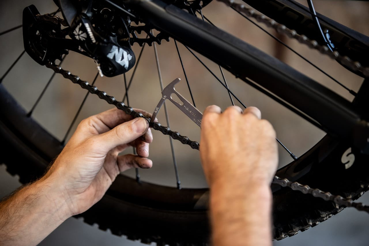 Person checking a bicycle chain using a chain checker