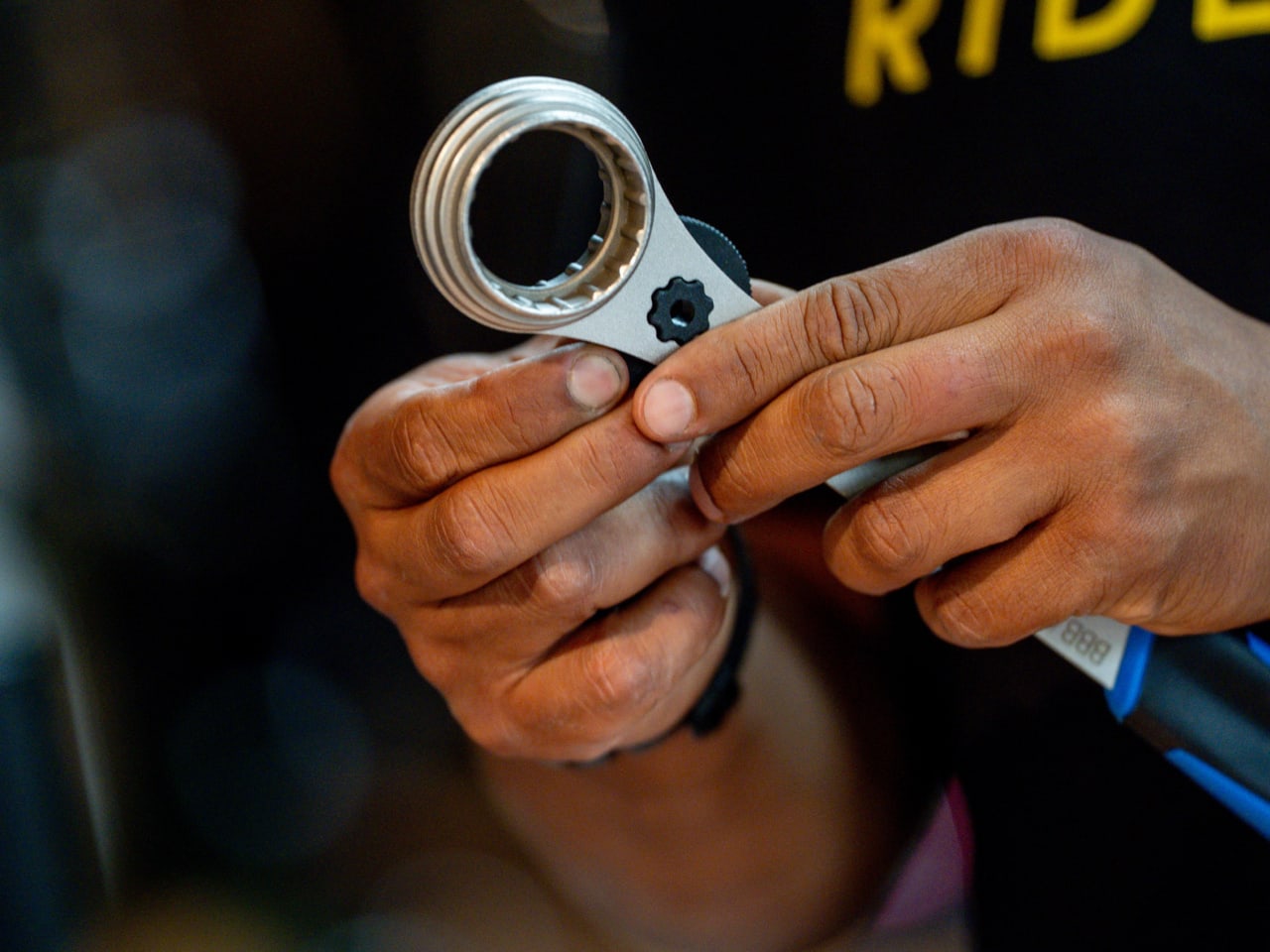 Close-up of hands holding a bicycle tool with a blurred background