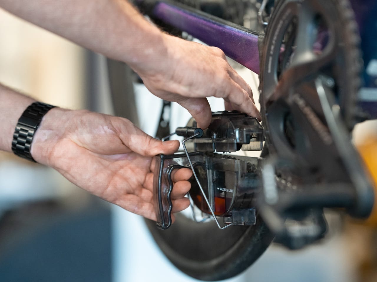 Close up of someone using a chain cleaner tool on a bike with a blurred background