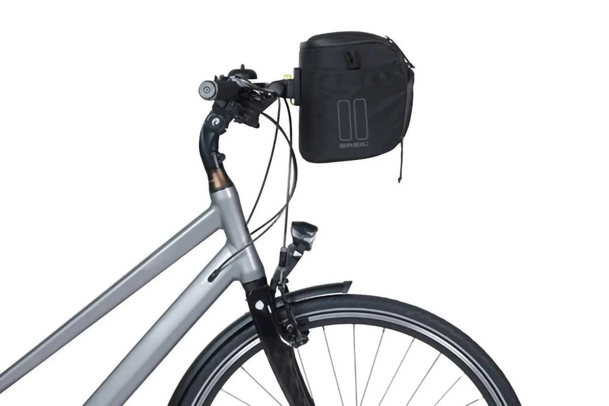A side view of a silver bike with a black Basil handlebar bag attached on a white background