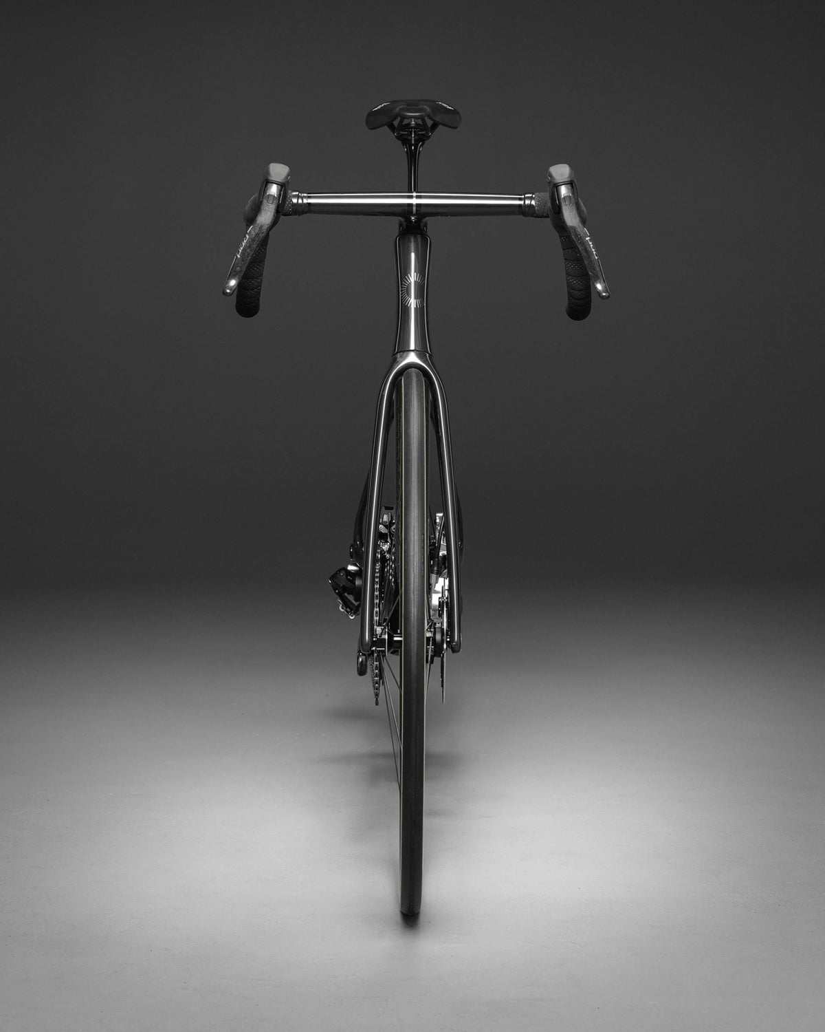 A front view of a metallic silver road bicycle with drop handlebars, set against a dark gray studio background.