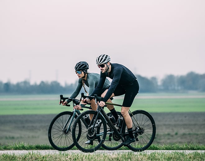 A couple riding side by side. The man is wearing Castelli bibshorts