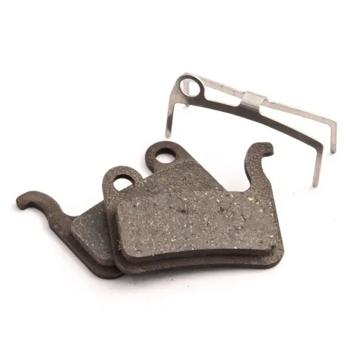 Two bicycle disc brake pads with a metal clip on a white background