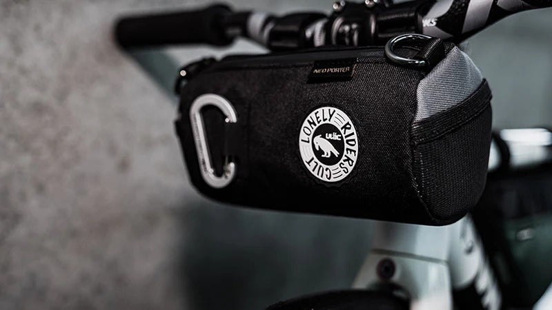 A handlebar bag attached to a mountain bike leaning against a wall