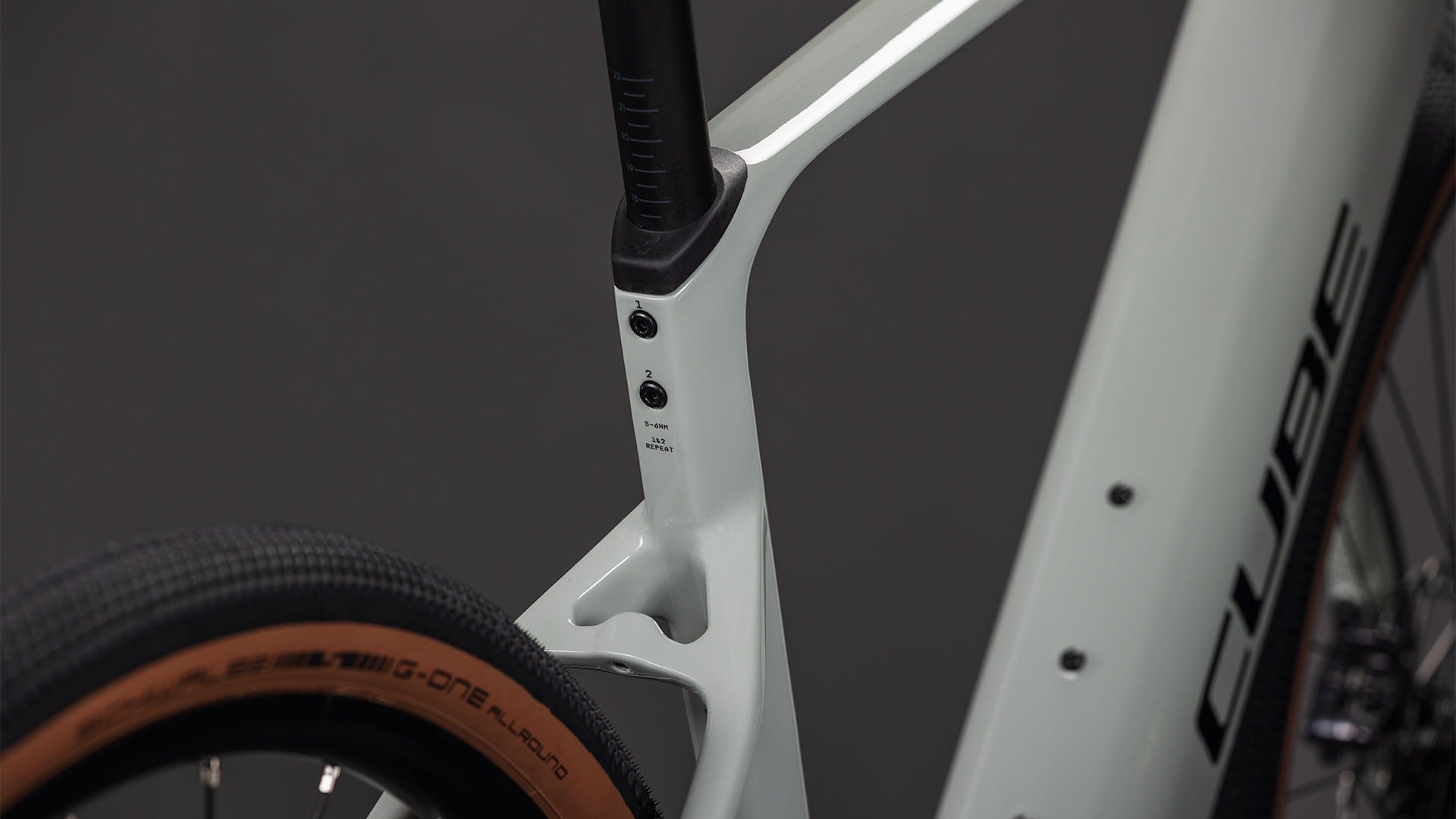 Close-up of the seat post of a beighe gravel bike frame with 'CUBE' branding on a dark background