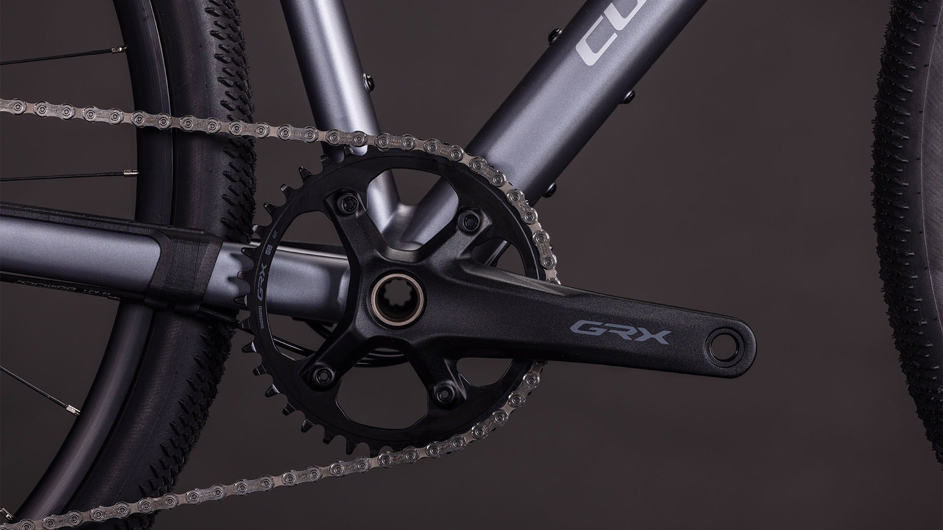 Close-up of a bicycle chain and gear system with 'GRX' branding on a dark background