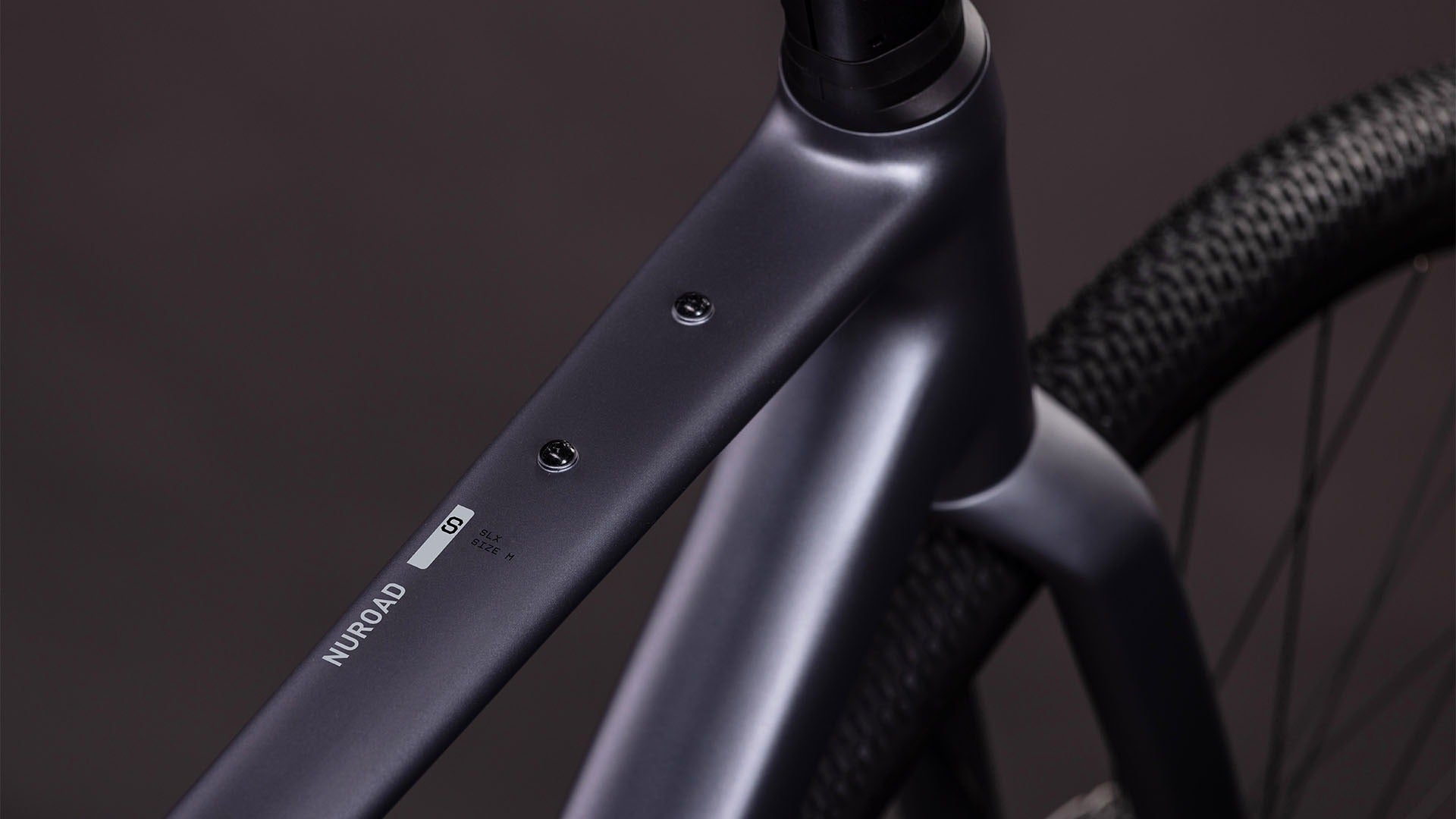 Close-up of the top tube of a bicycle frame with 'Nuroad' branding on a dark background