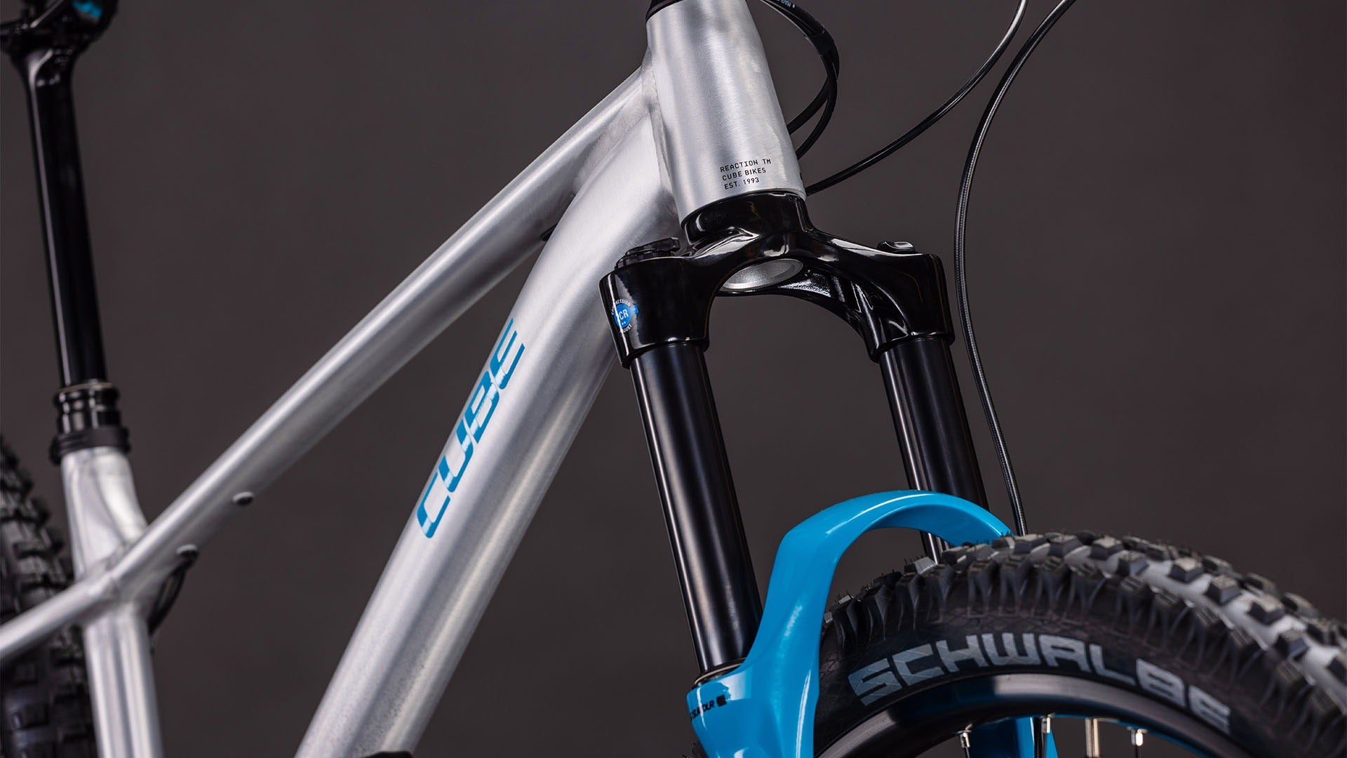 Close-up of the front fork of a Cube Silver and blue mountain bike on a dark background