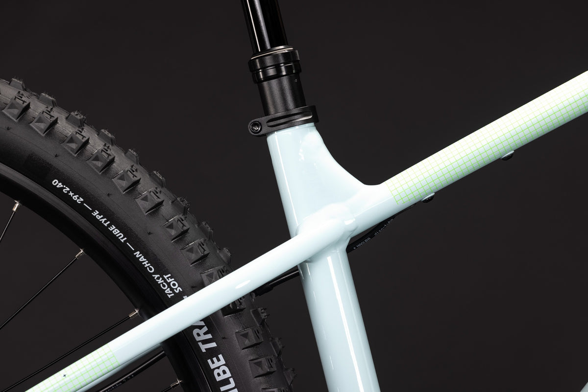A close up of a pale blue mountain bike seat post on a dark background
