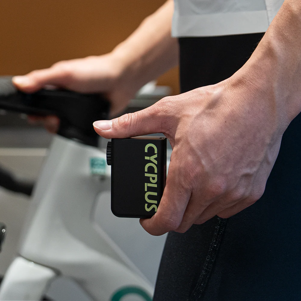 Person holding a black mini e-pump for bikes with 'CYCPLUS' branding in front of a blurred background