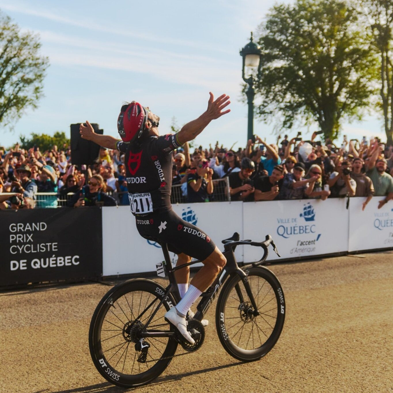 Cyclist celebrating on a bike in front of a cheering crowd at the Grand Prix Cycliste de Quebec.