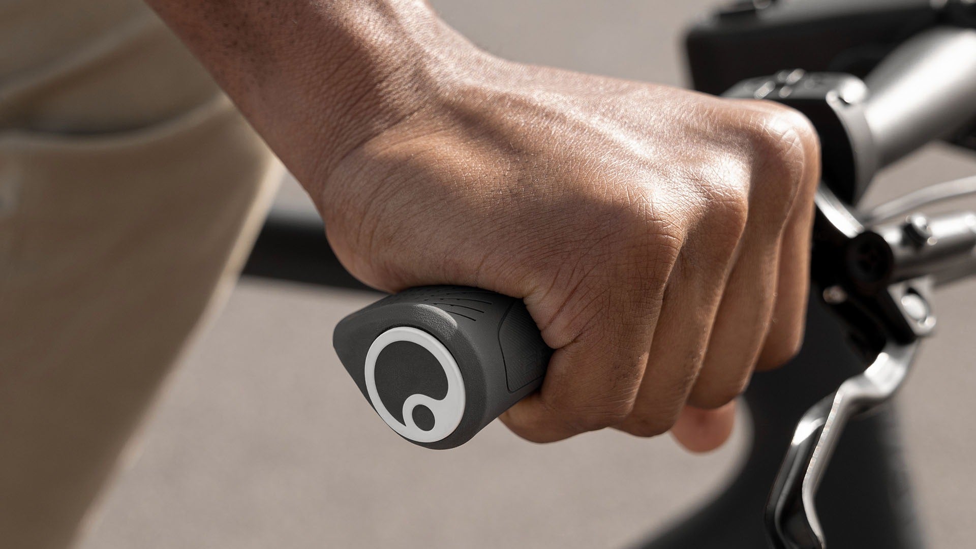 Hand gripping a bicycle handlebar with a visible brand logo.