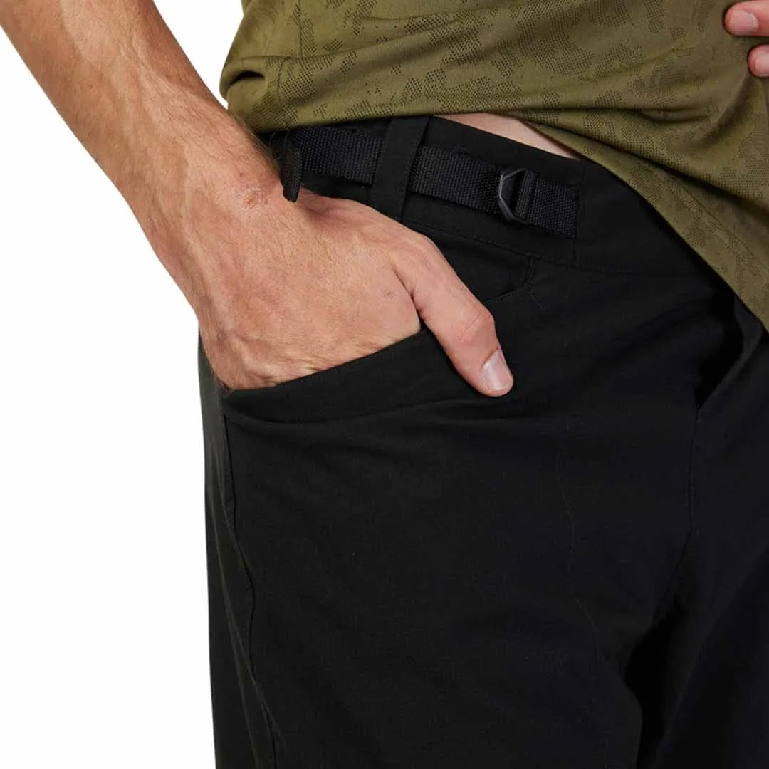 Person wearing a green shirt and black mountain bike shorts with a white background