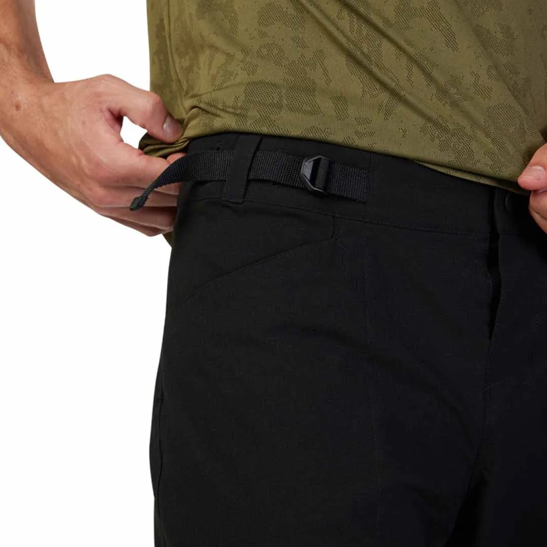 Person wearing a green shirt and black mountain bike shorts with a white background
