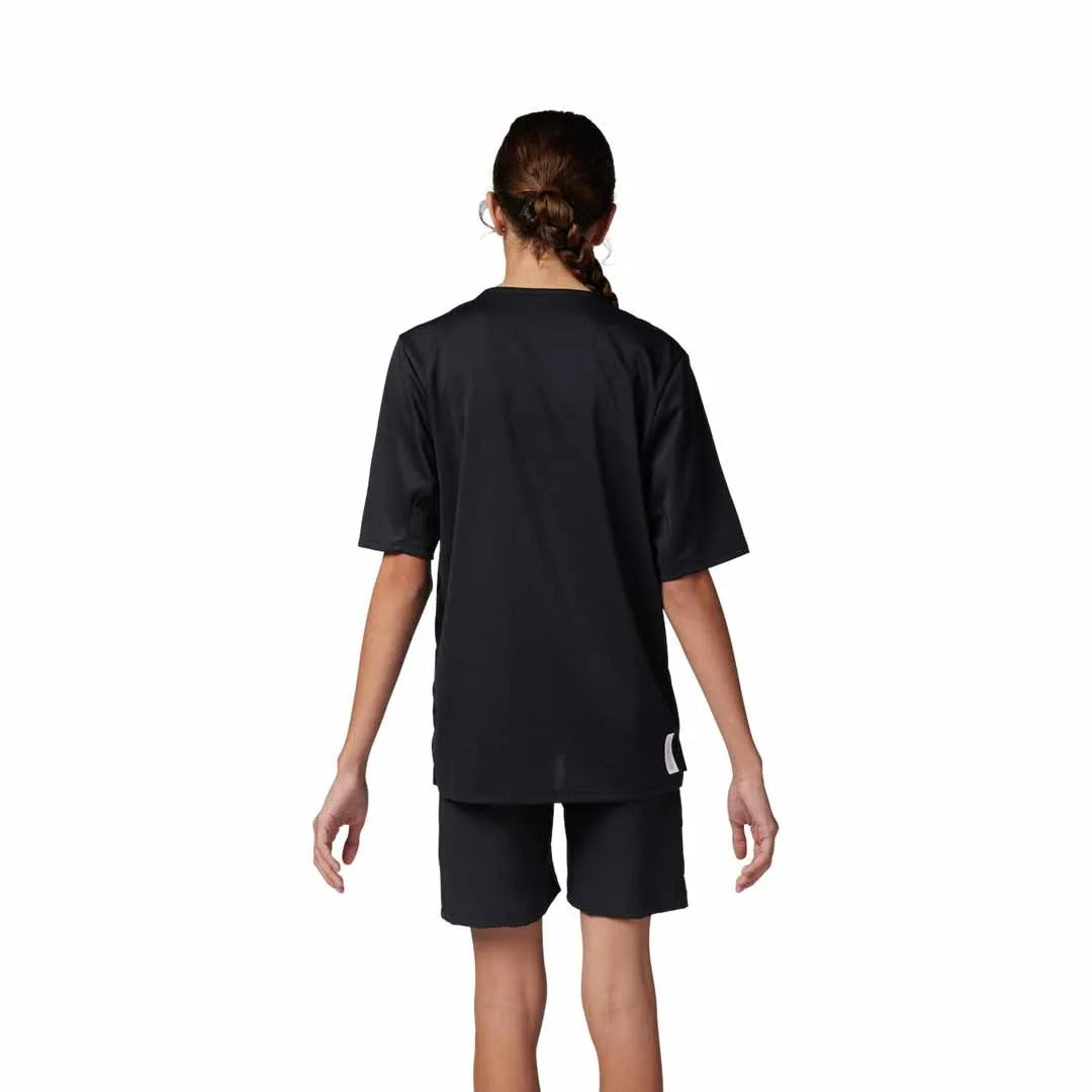 The rear view of a girl wearing a black mountain bike jersey and black mountain bike shorts on a white background