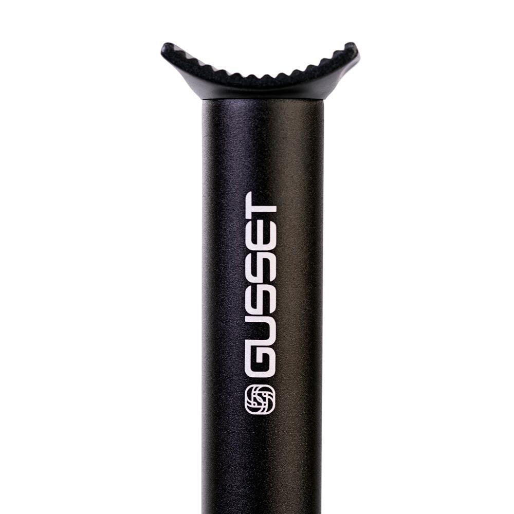 A close-up of a black bicycle seat post with the brand name 'GUSSET' printed vertically in white, featuring a textured black insert at the top, on a solid white background.