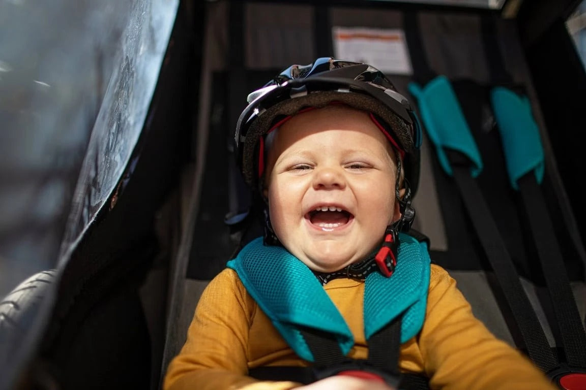 A child strapped into a kids trailer laughing