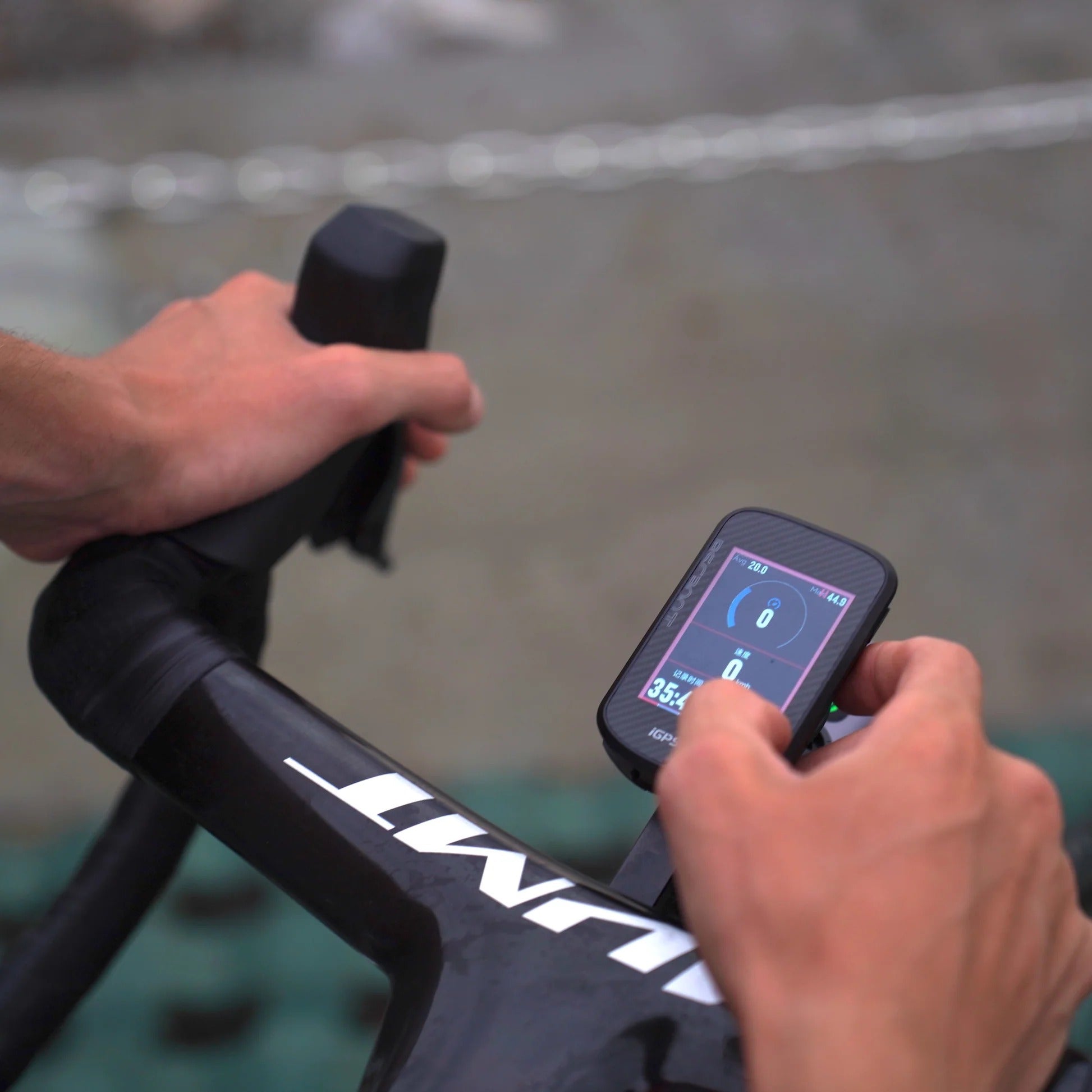 Person using a cycling computer on a roadbike handlebar with a blurred background