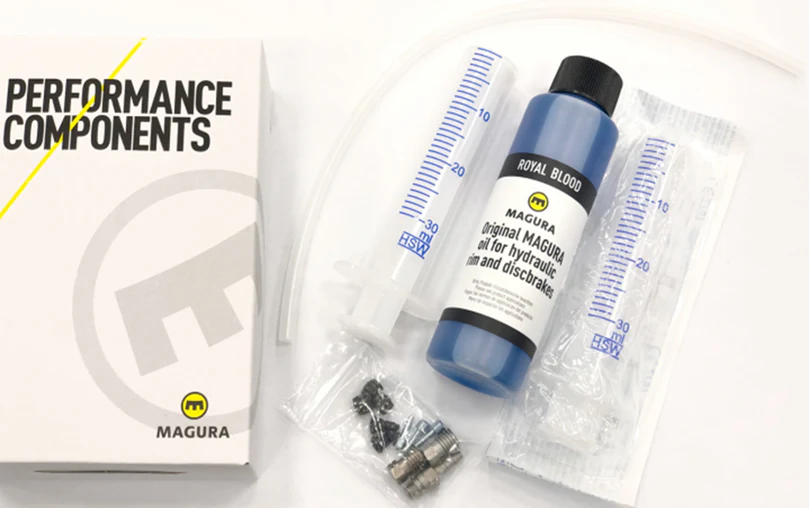 Magura Disc Brake Bleed kit containing a bottle of Magura Royal Blood hydraulic fluid, two plastic syringes, small metal fittings, and a branded white box on a white background.