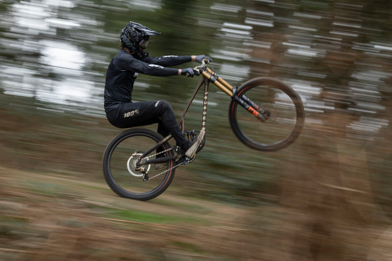 A person riding a downhill mountain bike wearing the 100% Airmatic MTB Gloves