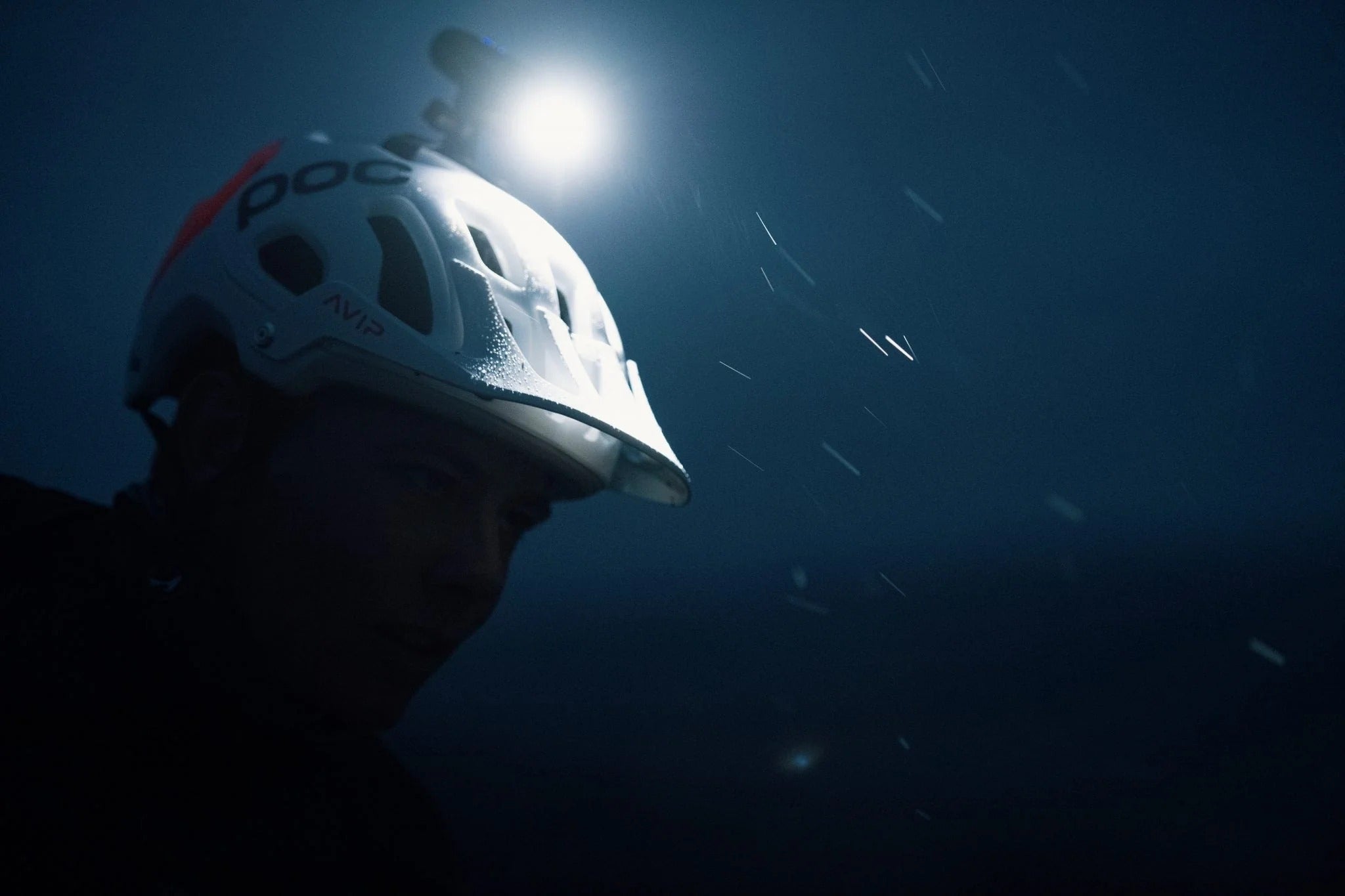 Person wearing a mountain bike helmet with a light mounted on top riding in the dark 