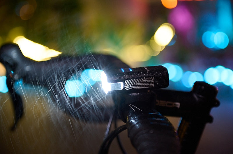 Road bike handlebar with bright front light  in the dark with rain pouring down