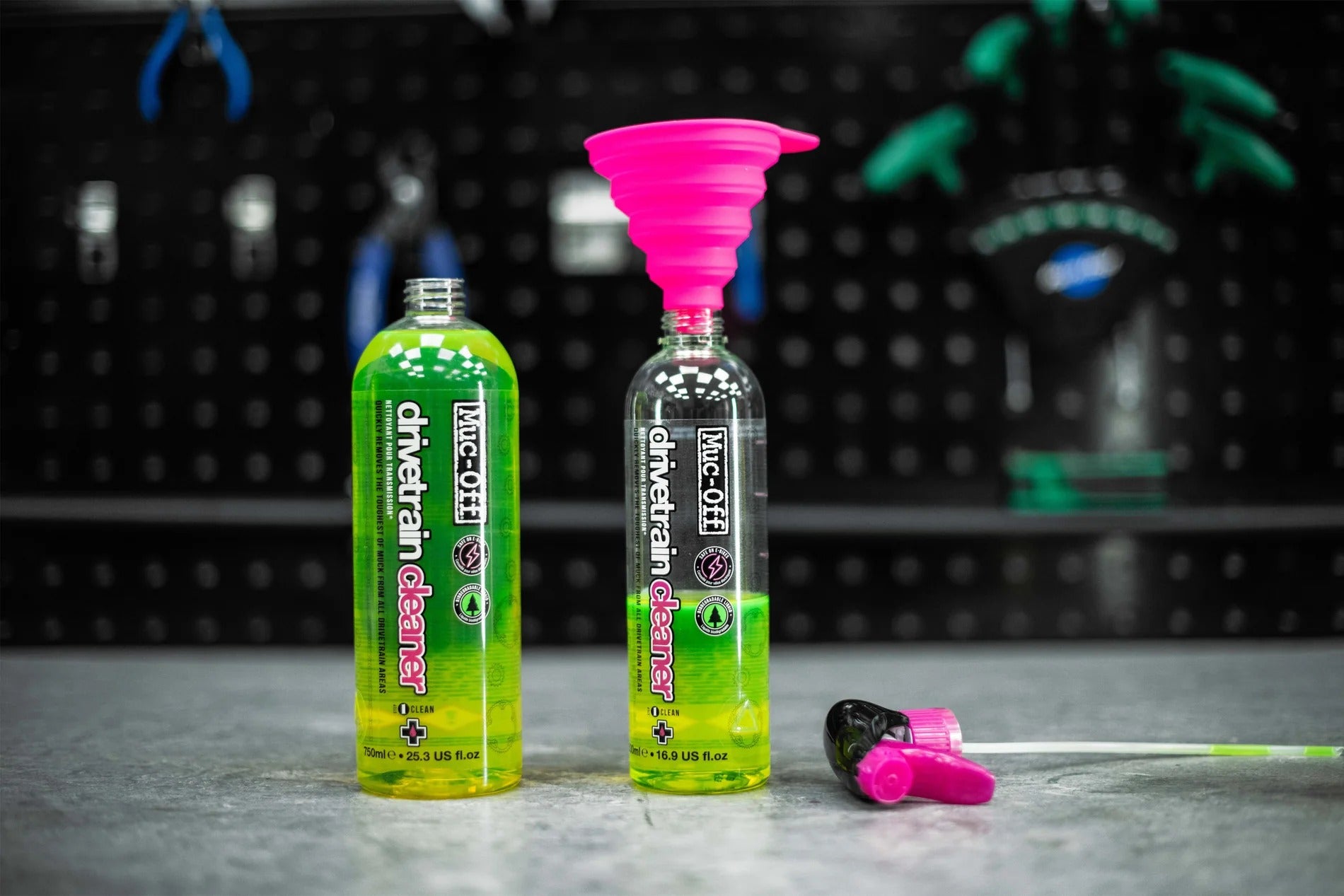 Muc-Off Drivetrain Cleaner being refilled into spray bottle with funnel on a blurred background