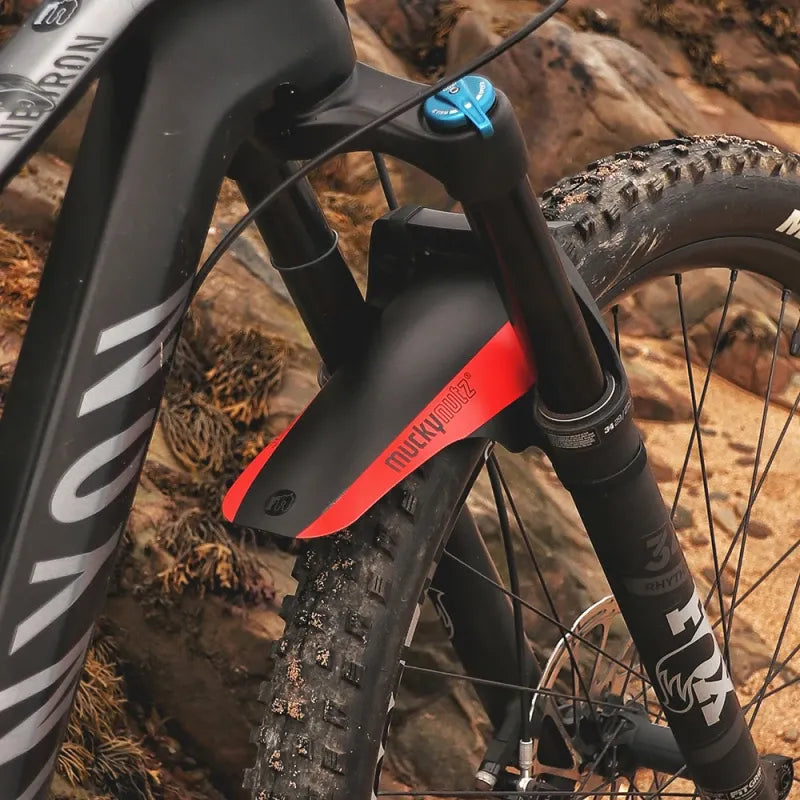 Close-up of a mountain bike with Mucky Nutz red and black fender on rocky terrain